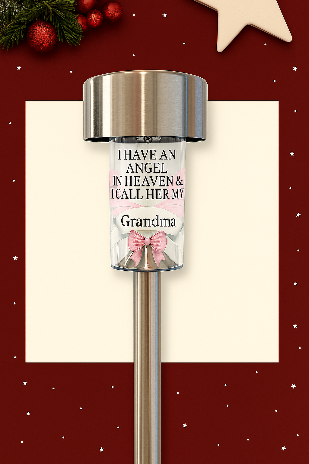 Stainless steel solar memorial light with personalised message for Grandma, featuring angel wings and a pink bow, set against a minimalistic Christmas background with snowflakes and festive greenery.