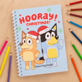 Coloring book titled 'Hooray Christmas!' with cartoon characters on a wooden surface with coloring pencils.