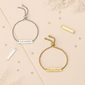 Two personalized adjustable bar bracelets—one gold and one silver—styled on a cream and beige background with frosted foliage. Engraved with “Love you always” and “A & N 15/02/2024,” ideal for gifting and keepsakes.