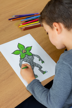 Child coloring a picture of a creature with plant-like features on a piece of paper.