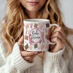 Person holding a mug with 'Boobie Warrior' design featuring pink ribbons and brown teddy bears.