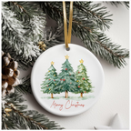 White ceramic ornament featuring three decorated Christmas trees topped with golden stars, with “Merry Christmas” in red cursive, hanging from a gold ribbon among pine branches.